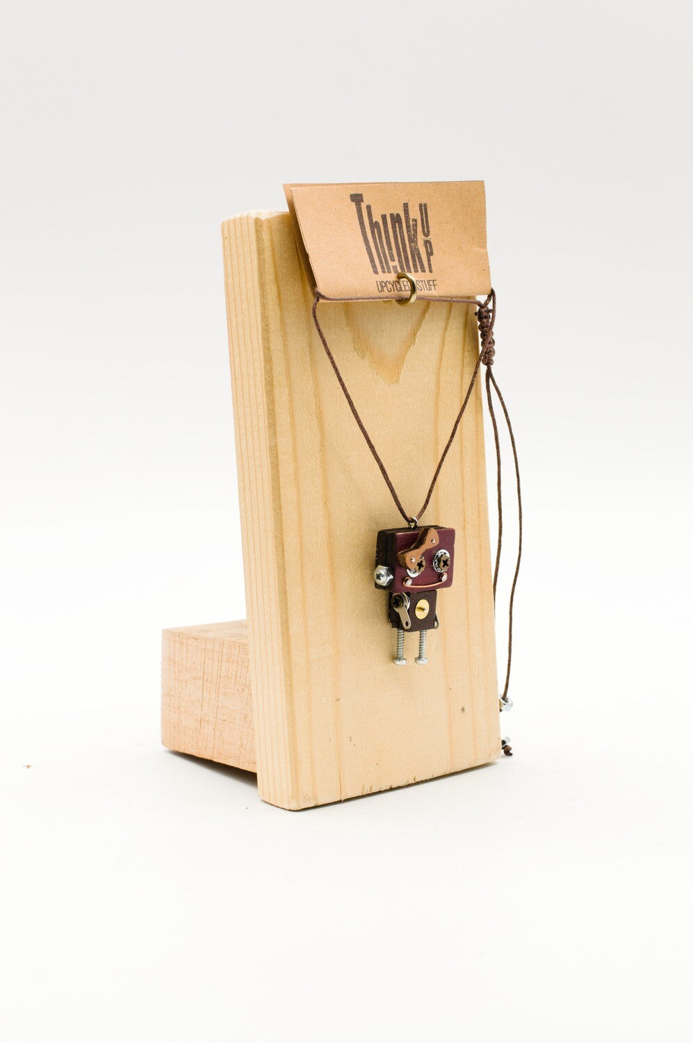 Ciondolo robot in legno tagliato a laser color marrone scuro con dettagli metallici e corda intrecciata su supporto in legno