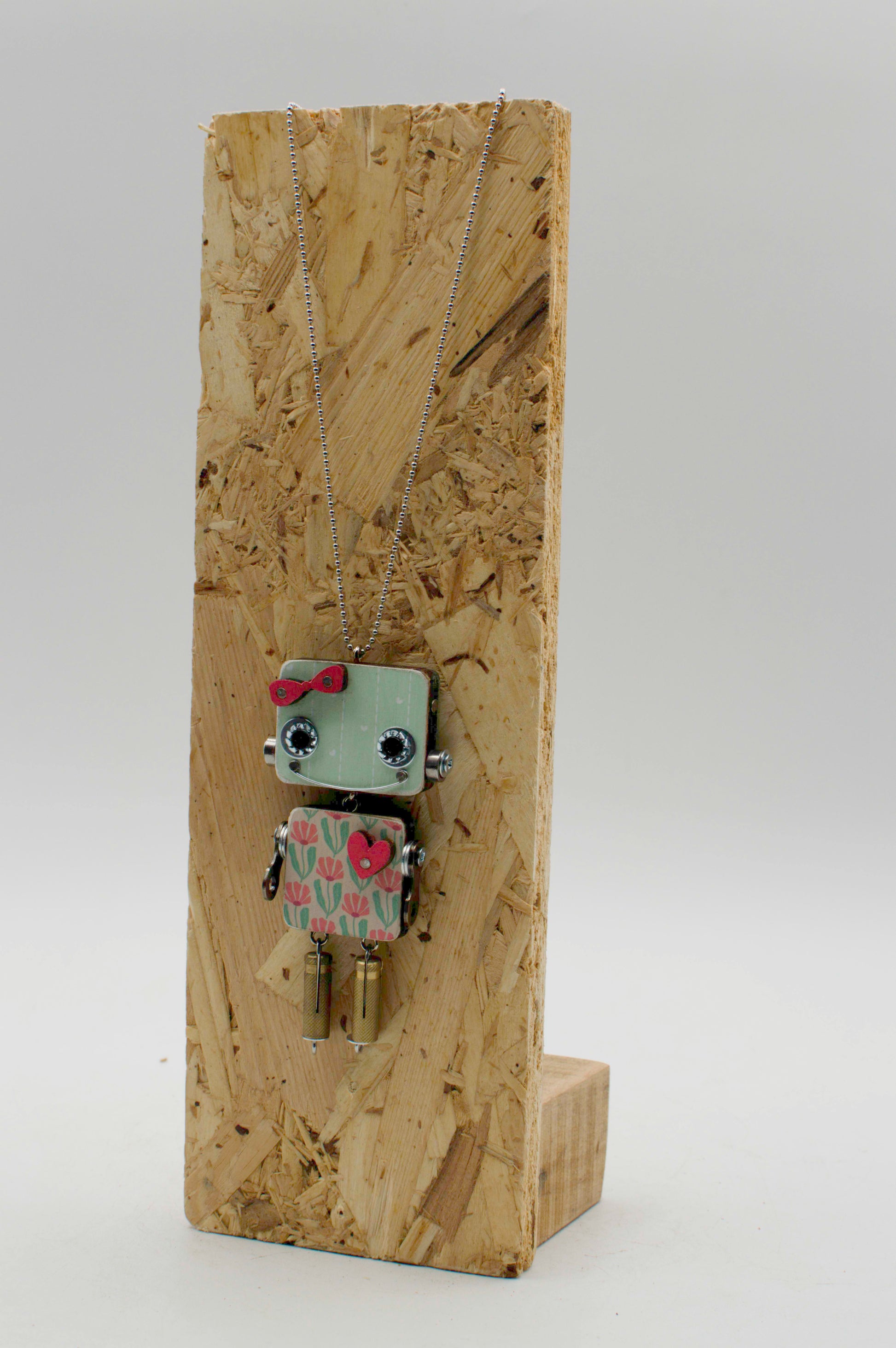 Ciondolo robot in legno tagliato a laser con testa verde chiaro occhi e giunti argentati fiocco rosso e tulipani rosa