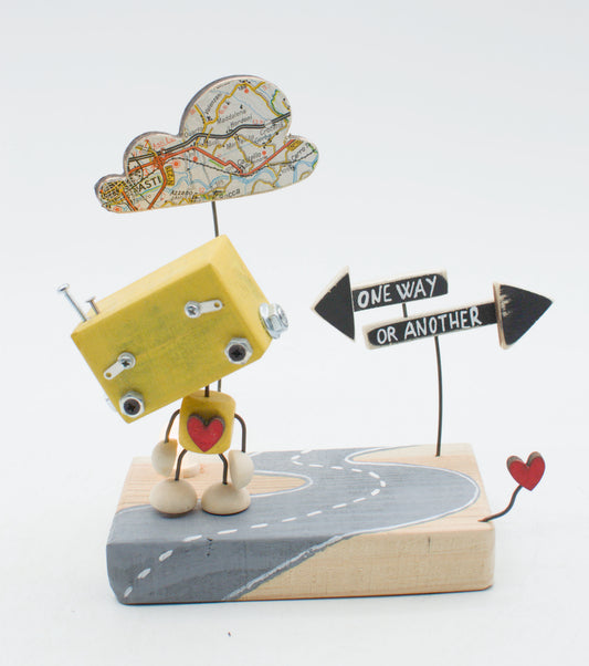 Diorama scultura luminosa robot giallo in legno con testa nuvola mappa e cuore sul petto accanto a segnaletica