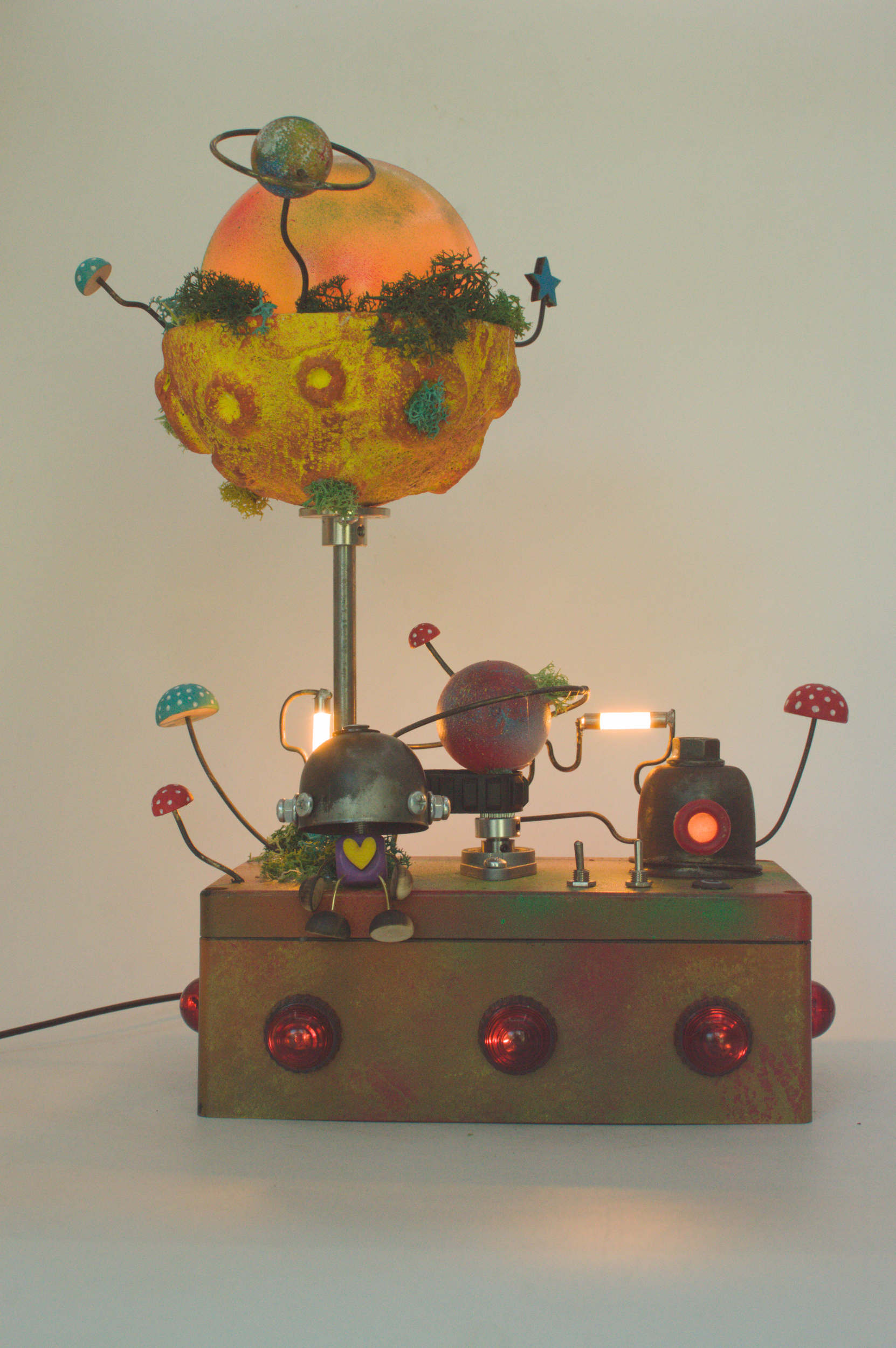 Lampada robot artigianale in metallo riciclato con paralume arancione a forma di pianeta e base metallica con luci rosse