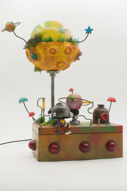 Lampada robot artigianale in metallo riciclato con globo giallo arancione decorato con muschio e pianeti su fili sottili
