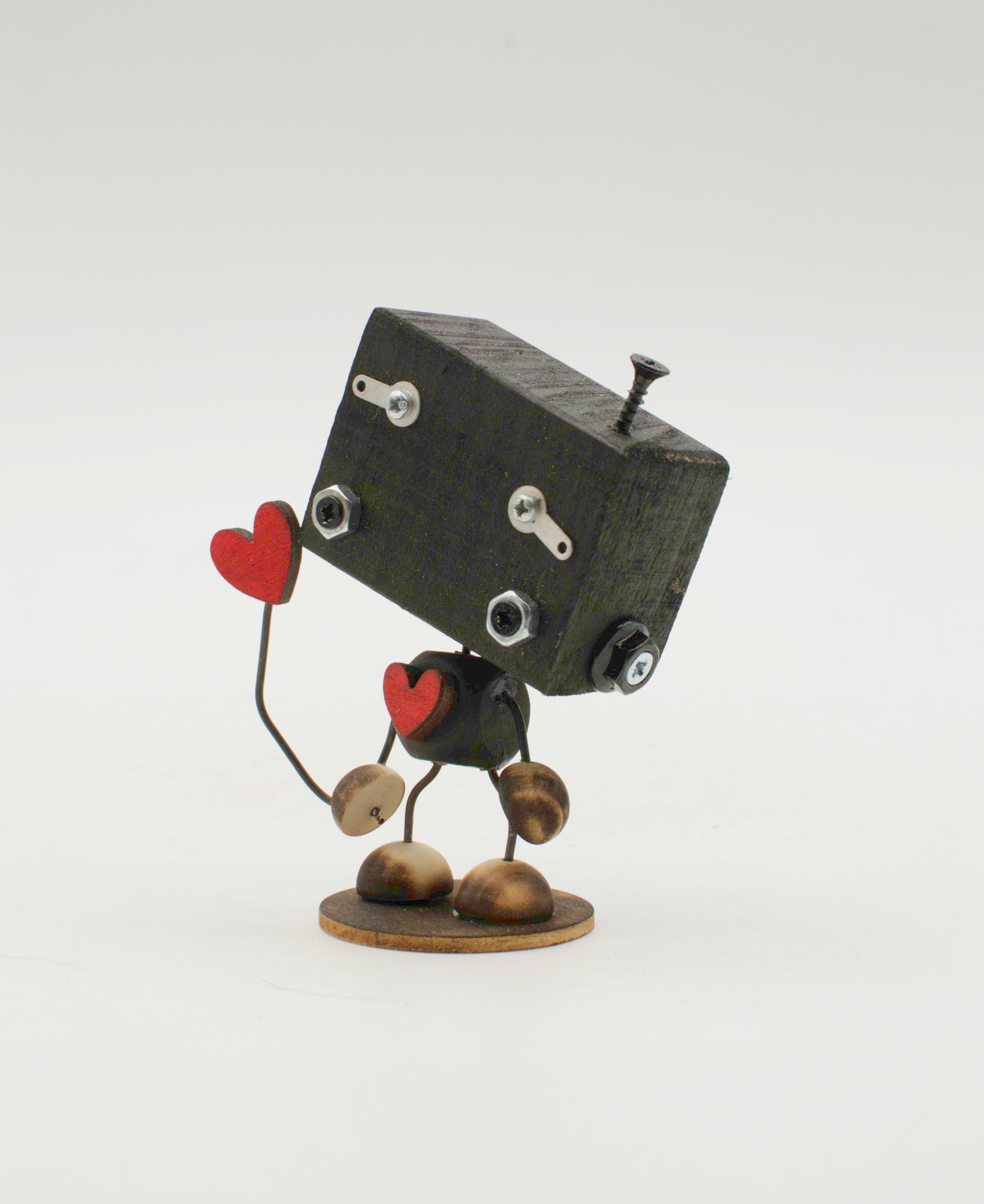 Minibot scultura robot fatto a mano in metallo nero con mani a forma di cuore rosse e piedi color ottone