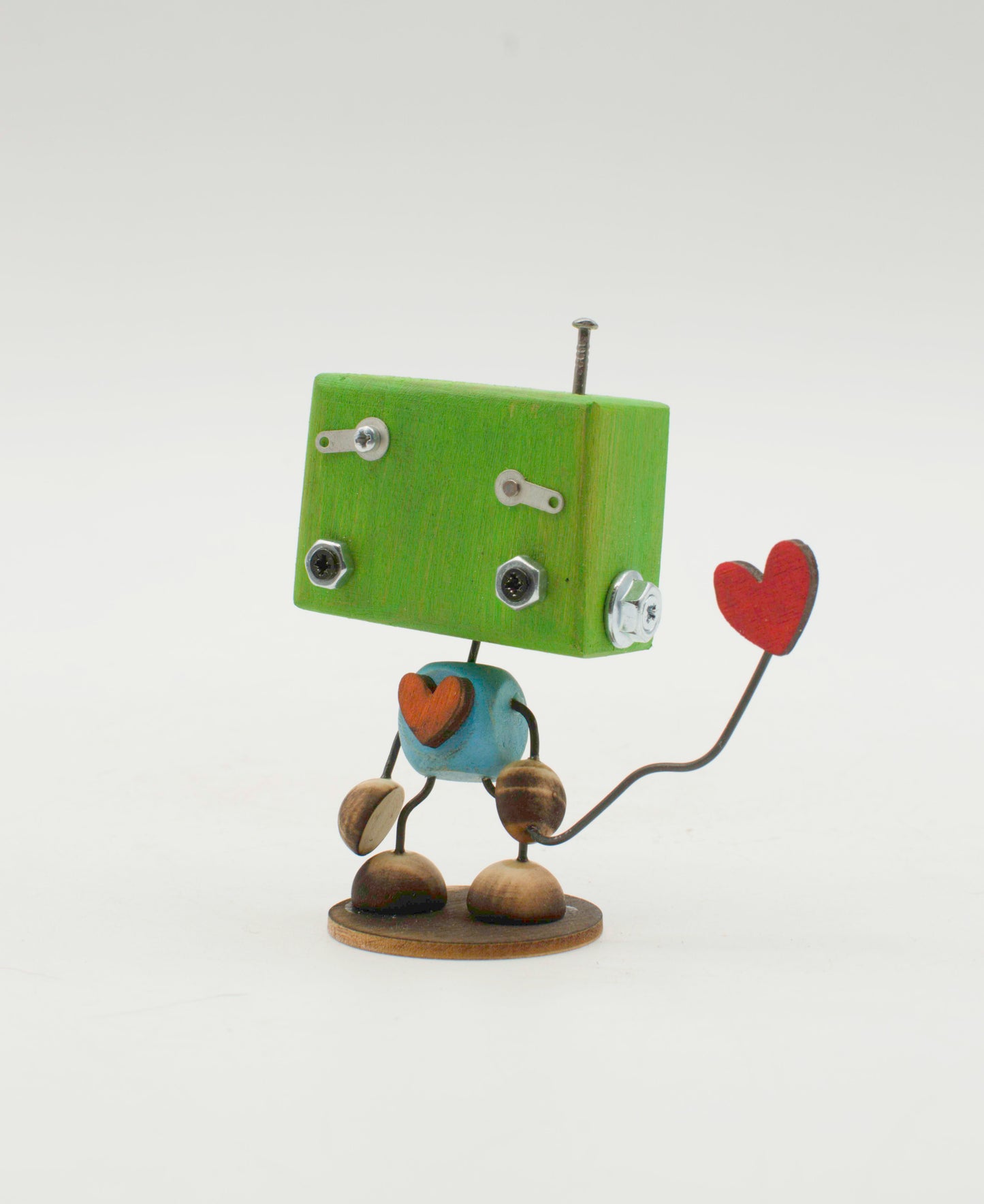 Minibot scultura robot fatto a mano verde con occhi a bulloni argento corpo blu sferico che tiene un cuore rosso su filo