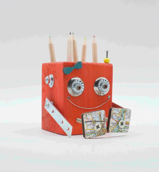 Portapenne a forma di robot in legno color pesca con occhi a ingranaggi argento, papillon blu e accessori a mappa