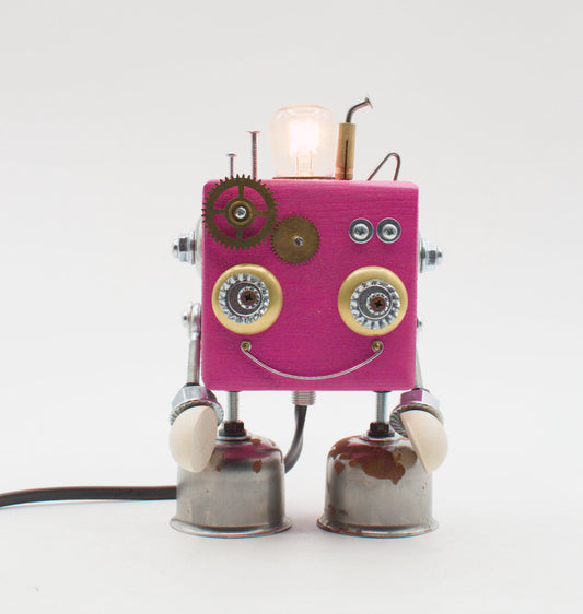 Lampada da tavolo cubot rosa con ingranaggi in ottone occhi metallici e volto sorridente in parti meccaniche riciclate