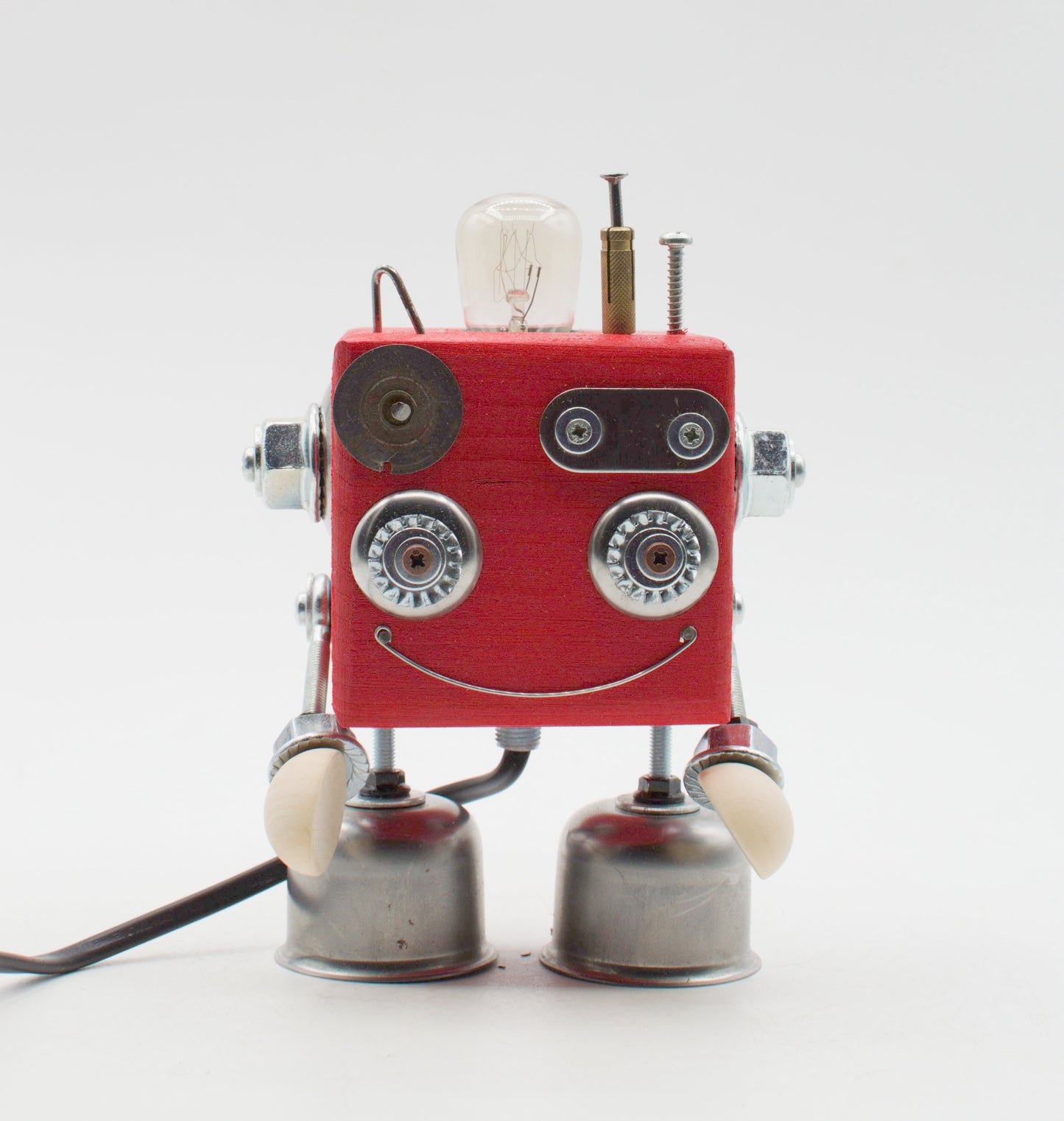Lampada da tavolo cubot rossa con corpo quadrato, occhi e sorriso argentati, braccia metalliche e bulbo esposto