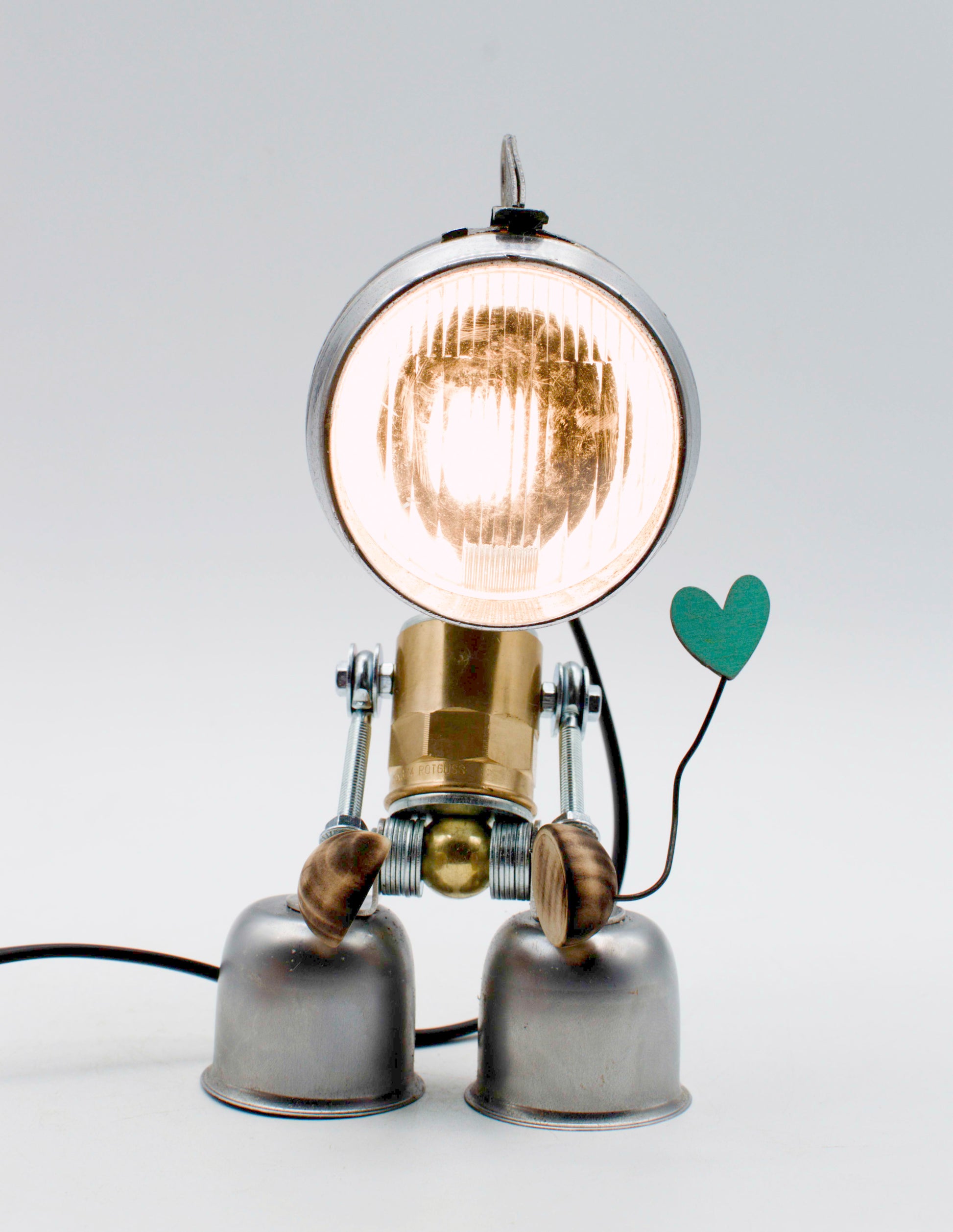 Lampada da tavolo robot steampunk in ottone e cromo con testa circolare e braccia articolate che tengono un cuore verde