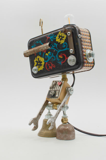 Robot lampada da tavolo stile fantasy handmade con testa rettangolare nera floreale e gambe in ottone e argento