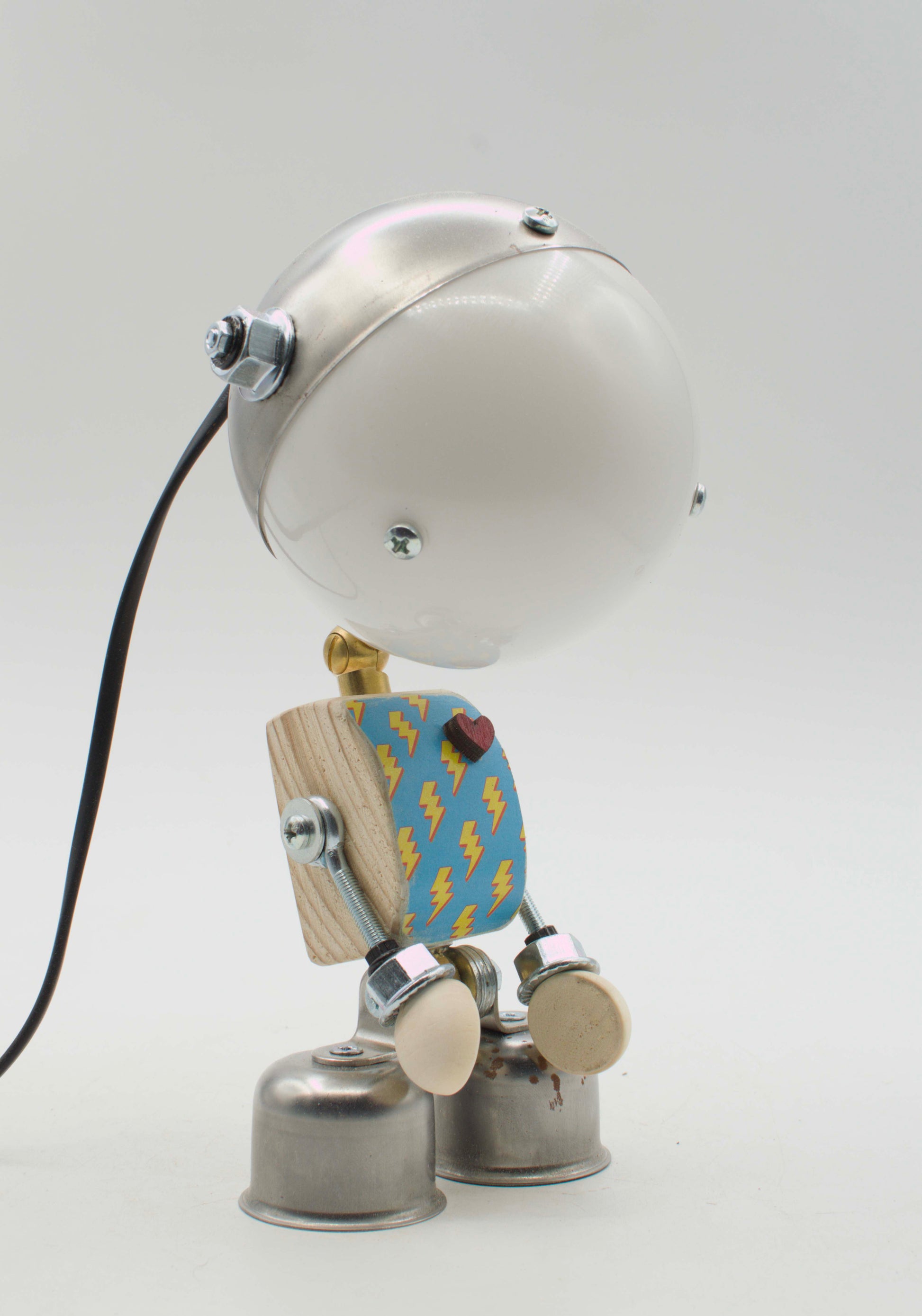 Lampada da tavolo robot kodama in metallo fatta a mano con testa rotonda argento, torso blu con fulmini e piedi a campana