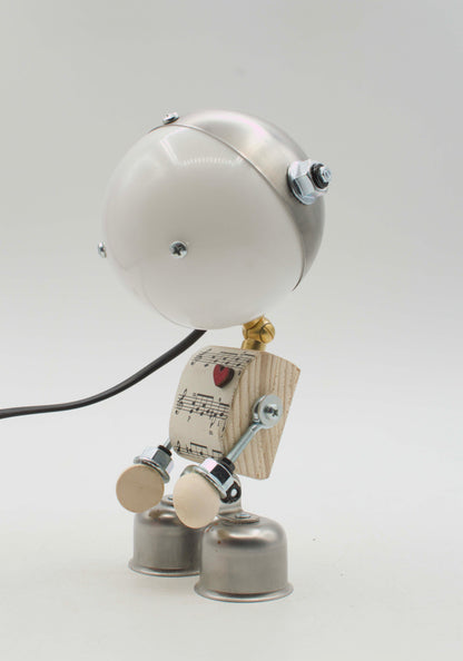 Robot lampada da tavolo stile kodama fatta a mano con testa sferica bianca, torso in legno con spartito e cuore rosso