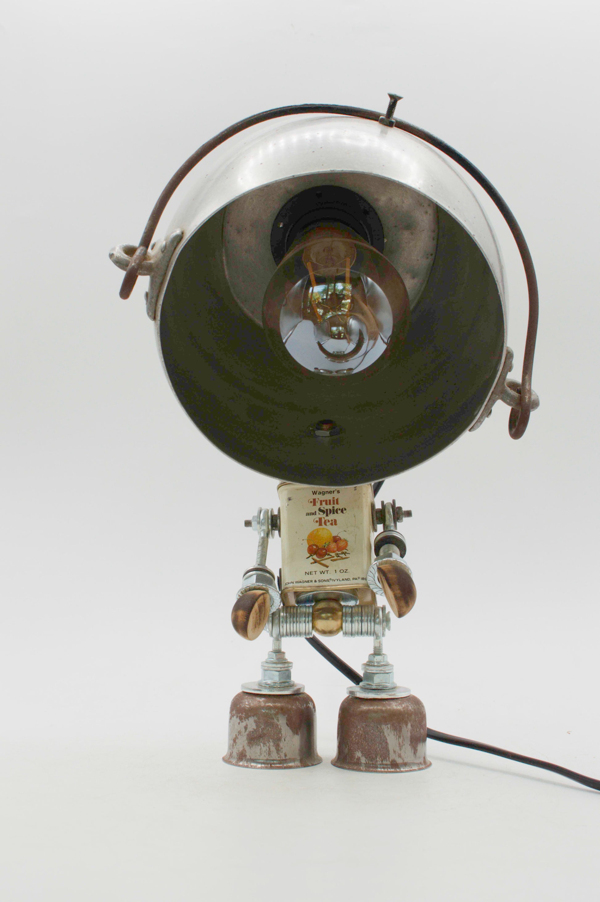 Robot lampada da tavolo stile pentolino con testa cromata, interno nero e arti metallici articolati