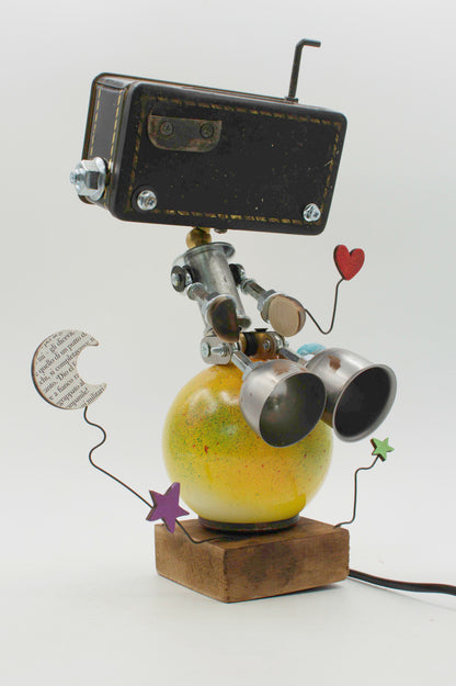 Lampada da tavolo stile pianeta robot con testa nera rettangolare braccia metalliche e base sferica giallo-verde