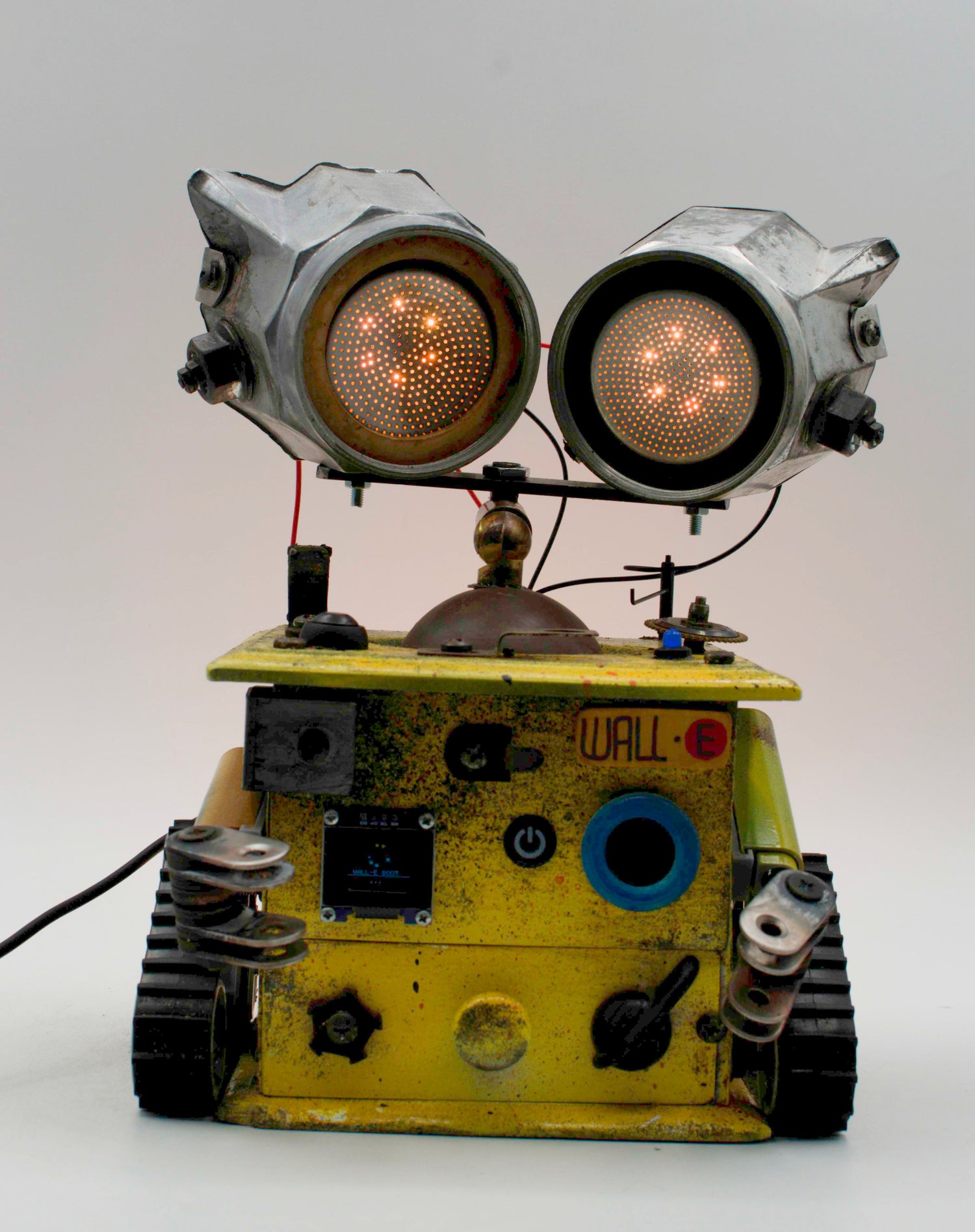 Graziosa lampada creata a mano stile wall e con robot metallico giallo e occhi led ambra luminosi su rotaie